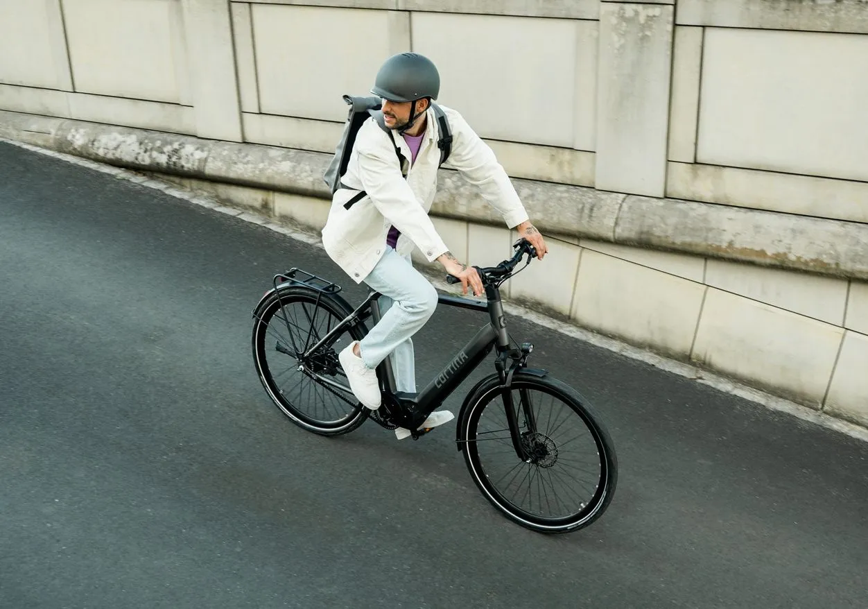 man with a helmet cycling on a cortina e-mozzo electric bike